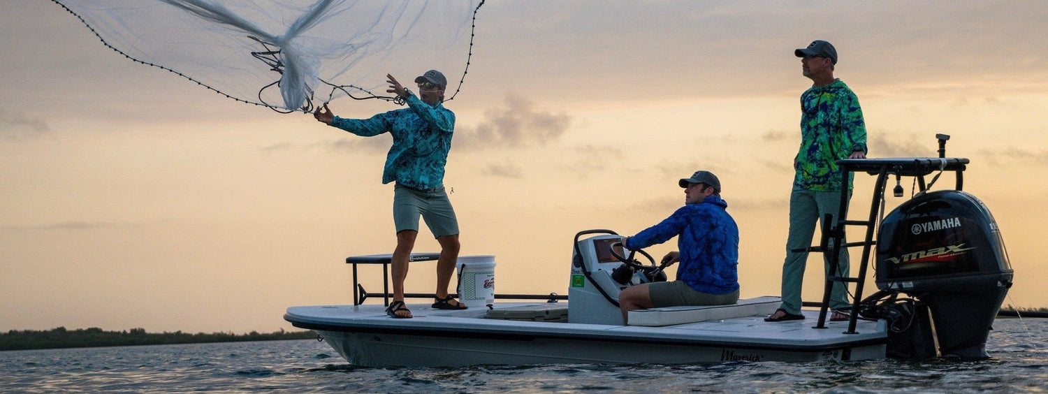 Three men decked out in Kryptek fishing hoodies on the water at sunset.